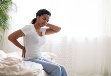 Mulher com sintomas da fibromialgia faz expressão de desconforto, exercícios podem proporcionar alívio das dores musculares.