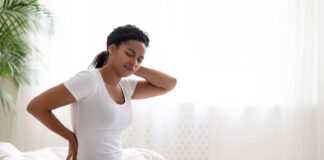 Mulher com sintomas da fibromialgia faz expressão de desconforto, exercícios podem proporcionar alívio das dores musculares.
