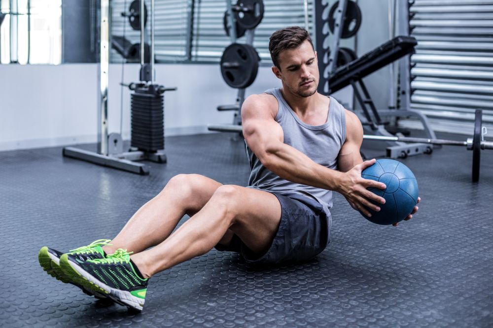 Homem realizando exercícios funcionais com medicine ball.