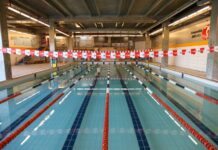 Piscina coberta da Cia Athletica, com raias demarcadas por boias vermelhas, pretas e brancas, prontas para treinos de natação.