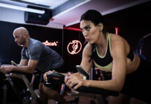 Duas pessoas realizam exercícios em bicicletas de spinning durante um treino na Cia Athletica.
