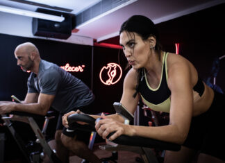 Duas pessoas realizam exercícios em bicicletas de spinning durante um treino na Cia Athletica.