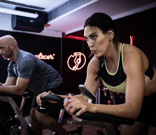 Duas pessoas realizam exercícios em bicicletas de spinning durante um treino na Cia Athletica.