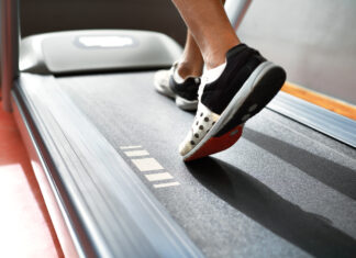 Esteira emagrece? Saiba como caminhada e corrida ajudam na perda de gordura Pessoa caminhando em uma esteira durante treino cardiovascular, com foco nos pés em movimento sobre a lona do equipamento, ilustrando caminhada e corrida como estratégias para emagrecimento e melhora do condicionamento físico.