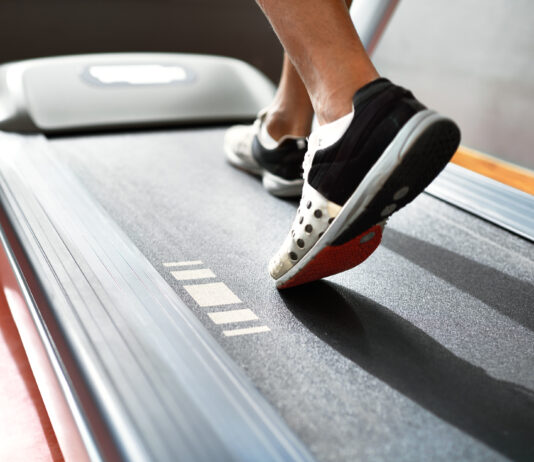 Esteira emagrece? Saiba como caminhada e corrida ajudam na perda de gordura Pessoa caminhando em uma esteira durante treino cardiovascular, com foco nos pés em movimento sobre a lona do equipamento, ilustrando caminhada e corrida como estratégias para emagrecimento e melhora do condicionamento físico.