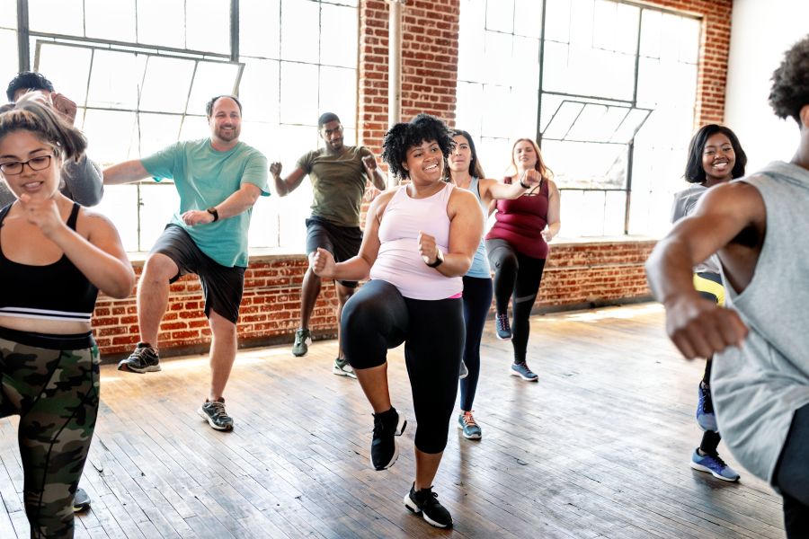 Grupo diverso participa de aula de dança em academia.