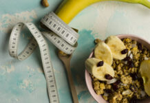 Fita métrica enrolada em uma banana ao lado de tigela com granola e frutas, representando alimentação saudável e déficit calórico.