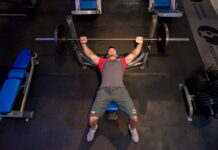 Homem faz treino de supino reto em academia