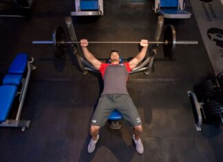 Homem faz treino de supino reto em academia