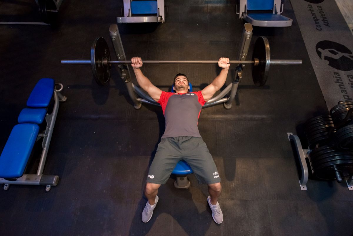 Homem faz treino de supino reto em academia