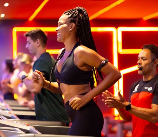 Treino para iniciante na academia: quais os exercícios para começar Mulher correndo na esteira com acompanhamento de professor em academia durante treino para iniciantes.