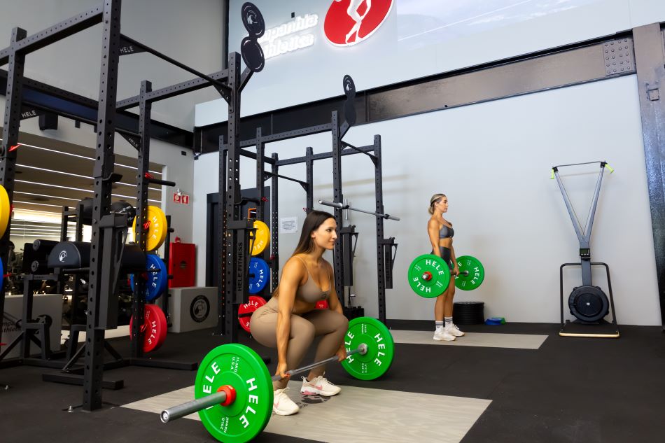 Mulheres levantando barra com anilhas para fazer exercício de levantamento terra.