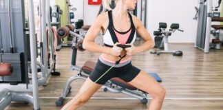 Mulher realizando exercício de resistência com faixa elástica na academia para fortalecer as pernas e melhorar a circulação.