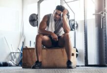 Homem na academia frustrado com seus treinos para musculação.
