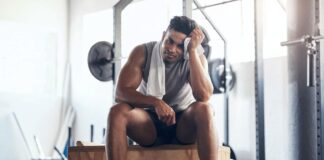 Homem na academia frustrado com seus treinos para musculação.