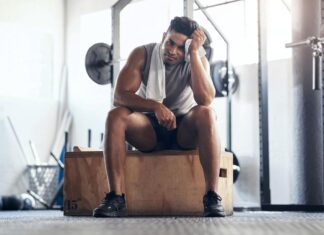 Homem na academia frustrado com seus treinos para musculação.