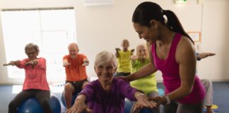 Idosos praticando pilates com bola em grupo, promovendo equilíbrio, mobilidade e bem-estar na terceira idade com acompanhamento profissional.