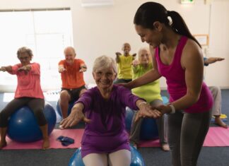 Idosos praticando pilates com bola em grupo, promovendo equilíbrio, mobilidade e bem-estar na terceira idade com acompanhamento profissional.