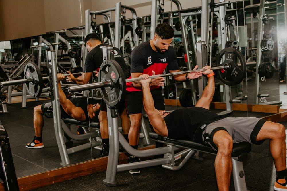 Homem praticando supino com barra em academia Homem praticando supino com barra em academia.
