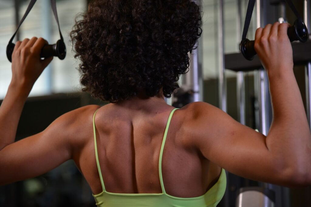 Mulher praticando musculação para as costas na academia.