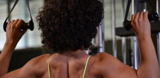 Mulher praticando musculação para as costas na academia.