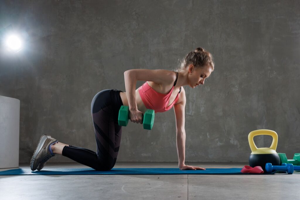 Mulher realizando remada unilateral com halter.