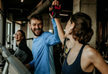 Um homem e mulher na esteira, celebrando com um "high five" após o treino na Cia Athletica, demonstrando como os exercícios em grupo promovem bem-estar e ajudam no controle da ansiedade.