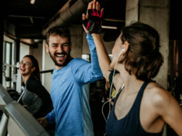 Sintomas da crise de ansiedade: como identificar e usar o treino a seu favor Um homem e mulher na esteira, celebrando com um "high five" após o treino na Cia Athletica, demonstrando como os exercícios em grupo promovem bem-estar e ajudam no controle da ansiedade.