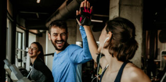 Um homem e mulher na esteira, celebrando com um "high five" após o treino na Cia Athletica, demonstrando como os exercícios em grupo promovem bem-estar e ajudam no controle da ansiedade.
