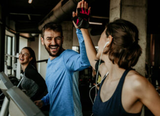 Sintomas da crise de ansiedade: como identificar e usar o treino a seu favor Um homem e mulher na esteira, celebrando com um "high five" após o treino na Cia Athletica, demonstrando como os exercícios em grupo promovem bem-estar e ajudam no controle da ansiedade.