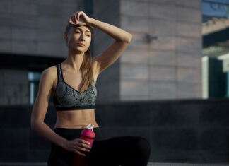 Mulher com expressão de cansaço após exercício segurando squeeze - sinais físicos do estresse no corpo feminino