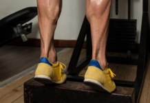 Exercício de elevação de panturrilha em step na academia para fortalecimento das pernas.