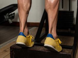 Exercício de elevação de panturrilha em step na academia para fortalecimento das pernas.