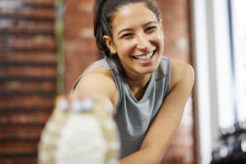 Mulher sorridente praticando exercício físico, demonstrando bem-estar e aumento de serotonina após treino na academia