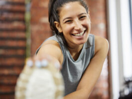 Mulher sorridente praticando exercício físico, demonstrando bem-estar e aumento de serotonina após treino na academia