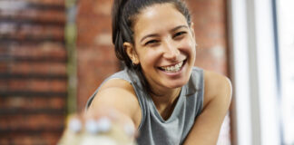 Serotonina e exercício físico: por que se movimentar faz tão bem para a mente Mulher sorridente praticando exercício físico, demonstrando bem-estar e aumento de serotonina após treino na academia