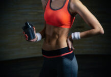 Pessoa treinando, com abdômen em destaque e segurando uma garrafa shaker, representando preparo físico e o uso consciente de suplementos termogênicos aliado ao treino.