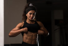 Mulher atleta exibindo definição muscular abdominal na academia, ilustrando fase de bulking e ganho de massa muscular.