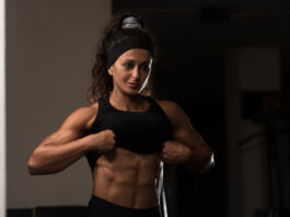 Mulher atleta exibindo definição muscular abdominal na academia, ilustrando fase de bulking e ganho de massa muscular.