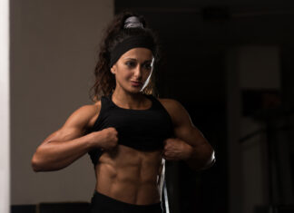 Mulher atleta exibindo definição muscular abdominal na academia, ilustrando fase de bulking e ganho de massa muscular.