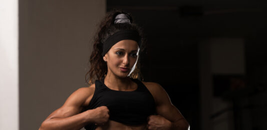 Mulher atleta exibindo definição muscular abdominal na academia, ilustrando fase de bulking e ganho de massa muscular.
