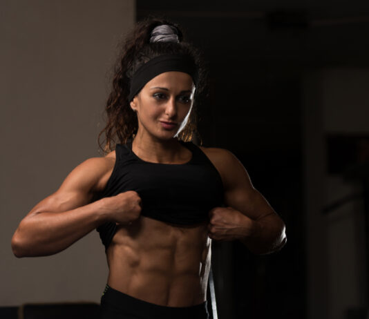 Mulher atleta exibindo definição muscular abdominal na academia, ilustrando fase de bulking e ganho de massa muscular.