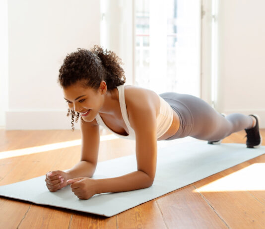 Mulher executando exercício de prancha abdominal em colchonete, fortalecendo o core.
