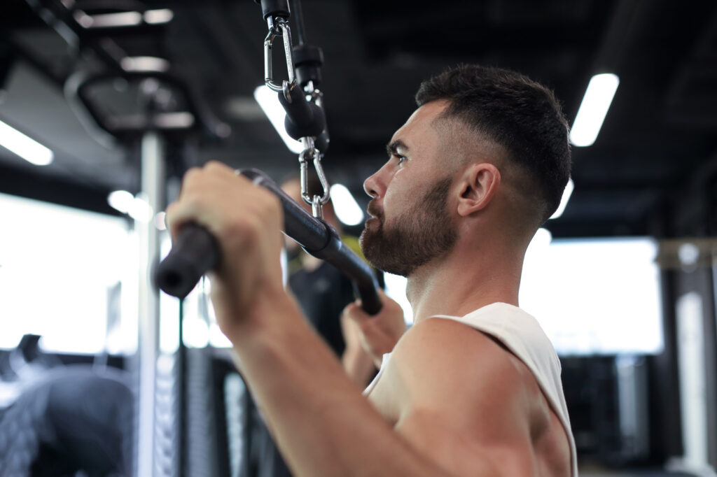 Atleta executando pulley pronado em equipamento profissional de academia - treino de costas
