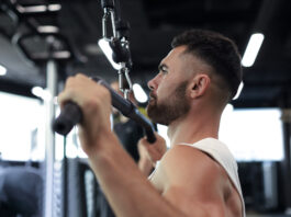Quer costas mais largas? Veja por que o pulley pronado não pode faltar no seu treino Atleta executando pulley pronado em equipamento profissional de academia - treino de costas