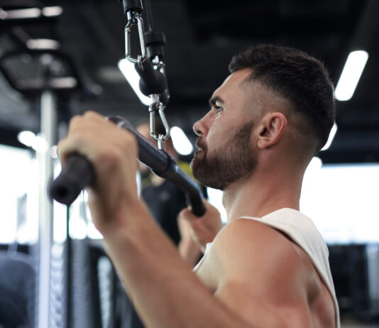 Atleta executando pulley pronado em equipamento profissional de academia - treino de costas