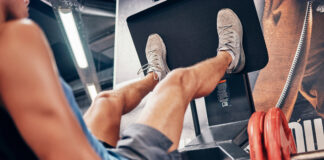 Homem realiza leg press em máquina durante treino de pernas na academia