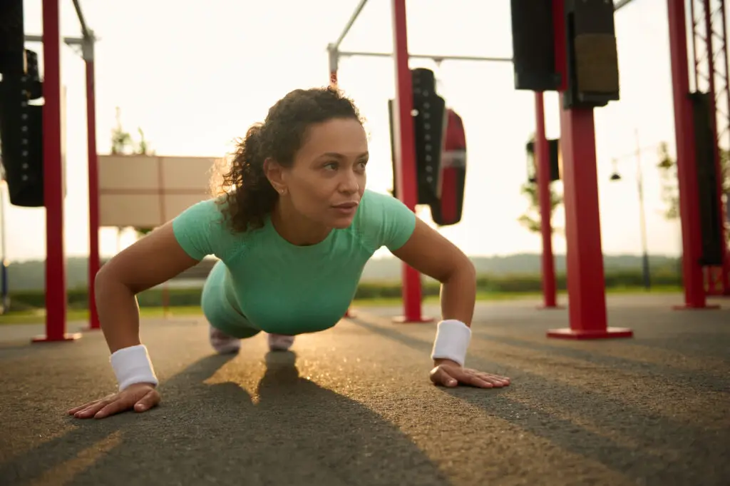 Mulher faz flexão de braços em treino funcional ao ar livre