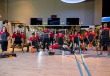 Instrutora corrige postura de aluna durante exercício com bola em academia.