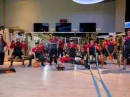 Instrutora corrige postura de aluna durante exercício com bola em academia.